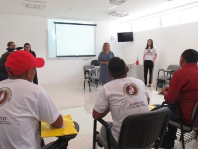 Pessoas sentadas enquanto duas mulheres estão de pé falando
