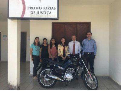 Equipe da Promotoria de Justiça posa com uma motocicleta.