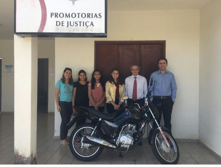 Equipe da Promotoria de Justiça posa com uma motocicleta.