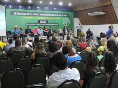 Pessoa sentadas em auditório assistindo a realização de evento