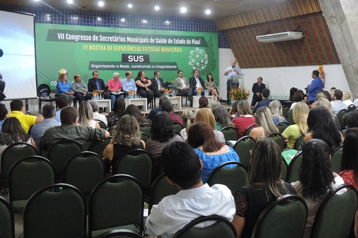 Pessoa sentadas em auditório assistindo a realização de evento