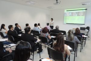Pessoas sentadas olhando mulher falando