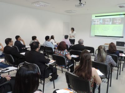 Pessoas sentadas olhando mulher falando