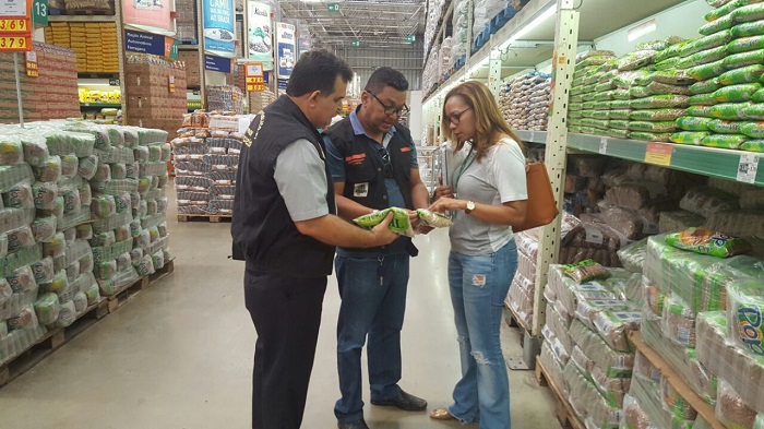 Três pessoas de pé segurando olhando a embalagem de um produto