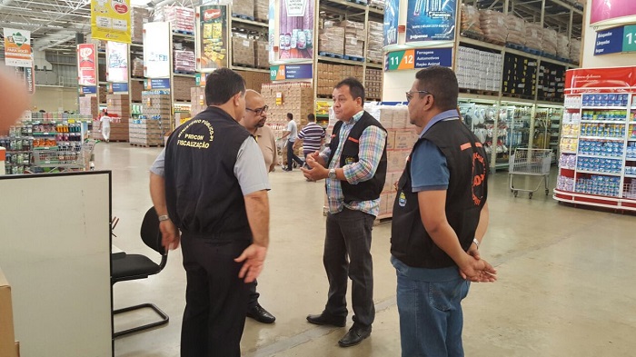 Quatro pessoas de pé conversando, ao fundo várias prateleiras de supermercado 