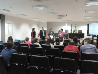 Quatro pessoas de pé enquanto as demais estão sentadas