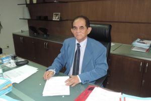 O Procurador-Geral de Justiça, Alípio de Santana Ribeiro, assina documentos sentado à sua mesa de trabalho.