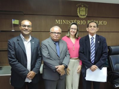 Quatro pessoas de pé, uma das pessoas está segurando um papel nas mãos