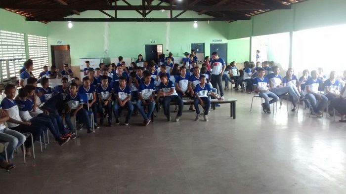Pessoas sentadas em cadeira no pátio de uma escola