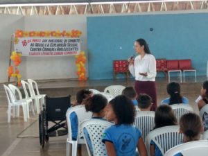 Mulher de pé falando para crianças