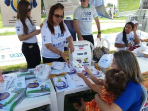 Ouvidora do MP entrega folder para senhora em estande.