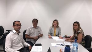 Quatro pessoas junto a uma mesa de reunião.