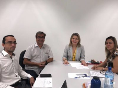Quatro pessoas junto a uma mesa de reunião.