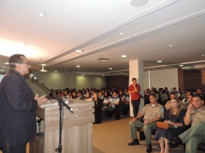 Homem falando para o público que está sentado no auditório