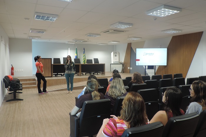 Pessoas sentadas em auditório e duas mulheres de pé