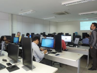 Pessoas sentadas em sala de aula observando um homem