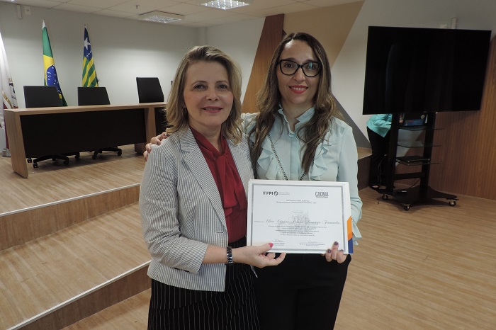 Duas mulheres de pé segurando um certificado 