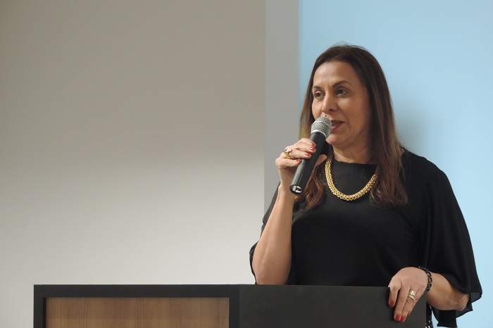 Mulher de pé falando com microfone nas mãos 