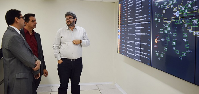 Três homens de pé olhando para monitor eletrônico 