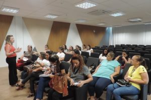 Promotora de Justiça Maria Eugênia Bastos fala em um auditório para várias professoras.