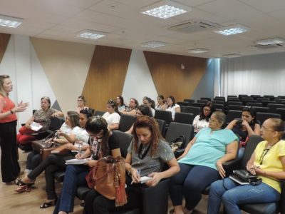 Promotora de Justiça Maria Eugênia Bastos fala em um auditório para várias professoras.