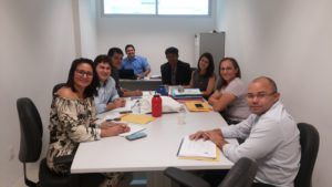 Pessoas reunidas em torno de uma mesa, em uma sala de reuniões.