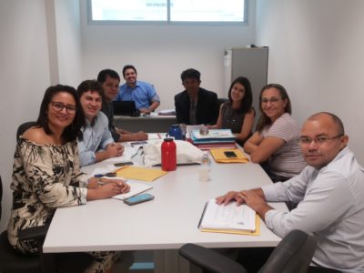 Pessoas reunidas em torno de uma mesa, em uma sala de reuniões.