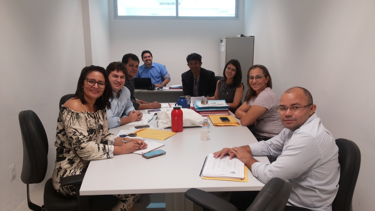 Pessoas reunidas em torno de uma mesa, em uma sala de reuniões.