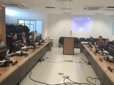 Pessoas ao redor de mesa em U, operando computadores.