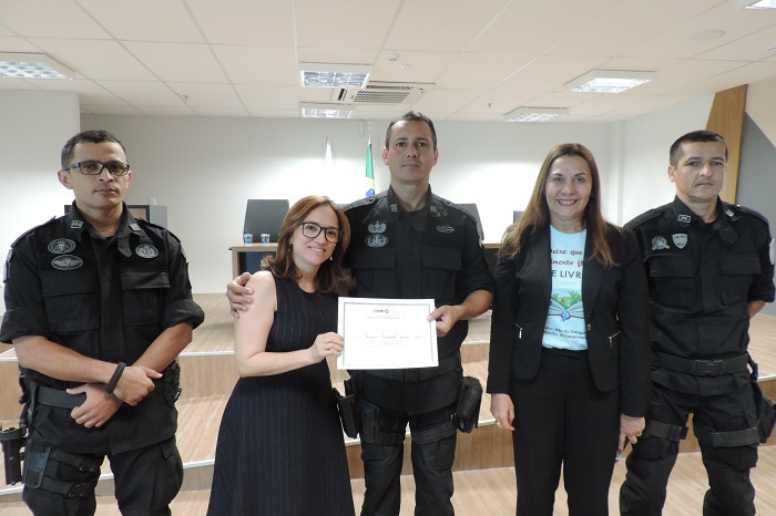 Pessoas de pé, duas seguram um certificado 