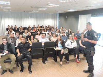Pessoas sentadas e um homem de pé com microfone nas mãos