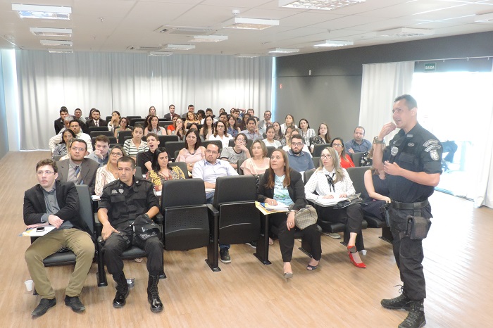Pessoas sentadas e um homem de pé com microfone nas mãos