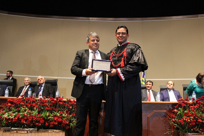 Duas pessoas de pé segurando um placa 