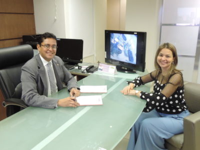 Procurador-Geral de Justiça assinando documentos em sua mesa de trabalho. Sentada à sua frente, está a Assessora Especial de Planejamento e Gestão, Itanieli Rotondo.