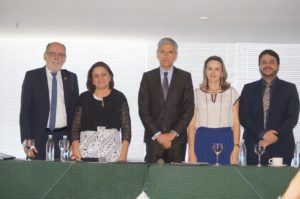 Pessoas em uma mesa de honra, posando de pé.