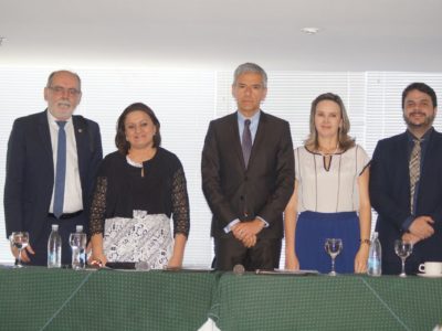 Pessoas em uma mesa de honra, posando de pé.