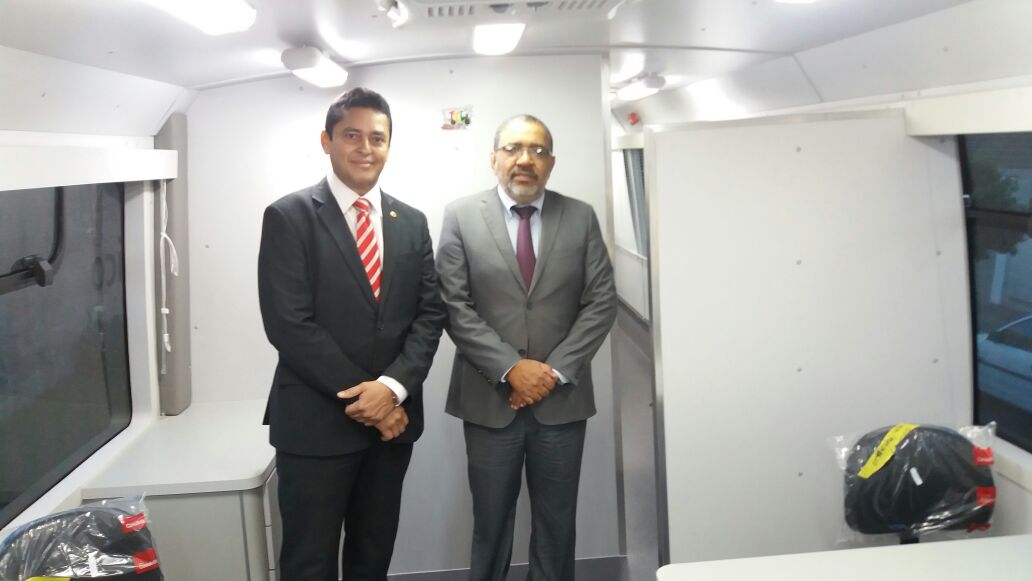 Dois homens de terno dentro de um ônibus mobiliado.