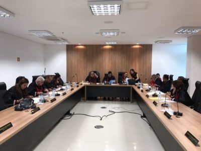 Reunião do Colégio de Procuradores de Justiça. Pessoas trajadas de beca e sentadas diante de uma mesa em formato de U.