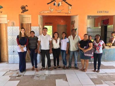 Pessoas de pé, uma ao lado da outra, no pátio de uma escola