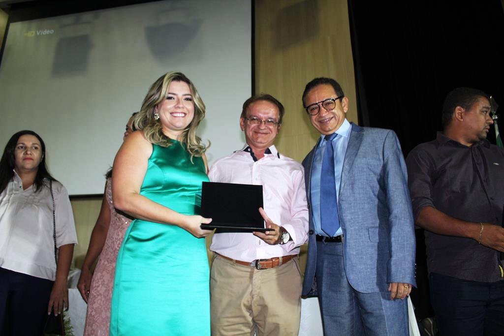Três pessoas de pé duas, estão segurando uma placa com as mãos 