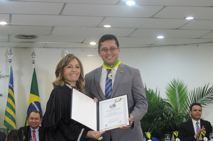Duas pessoas segurando um livro de pé e sorrindo para fotografia 