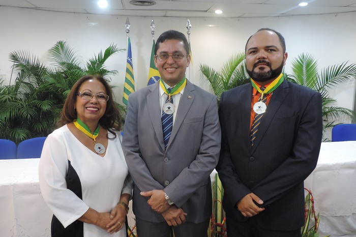 Três pessoas de pé sorrindo para fotografia, no pescoço está o colar do mérito do Tribunal de Contas do Piauí 