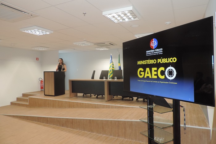 Mulher de pé com microfone nas mãos falando 