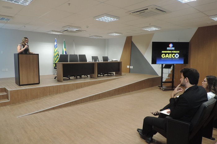 Mulher de pé na tribuna com microfone nas mãos