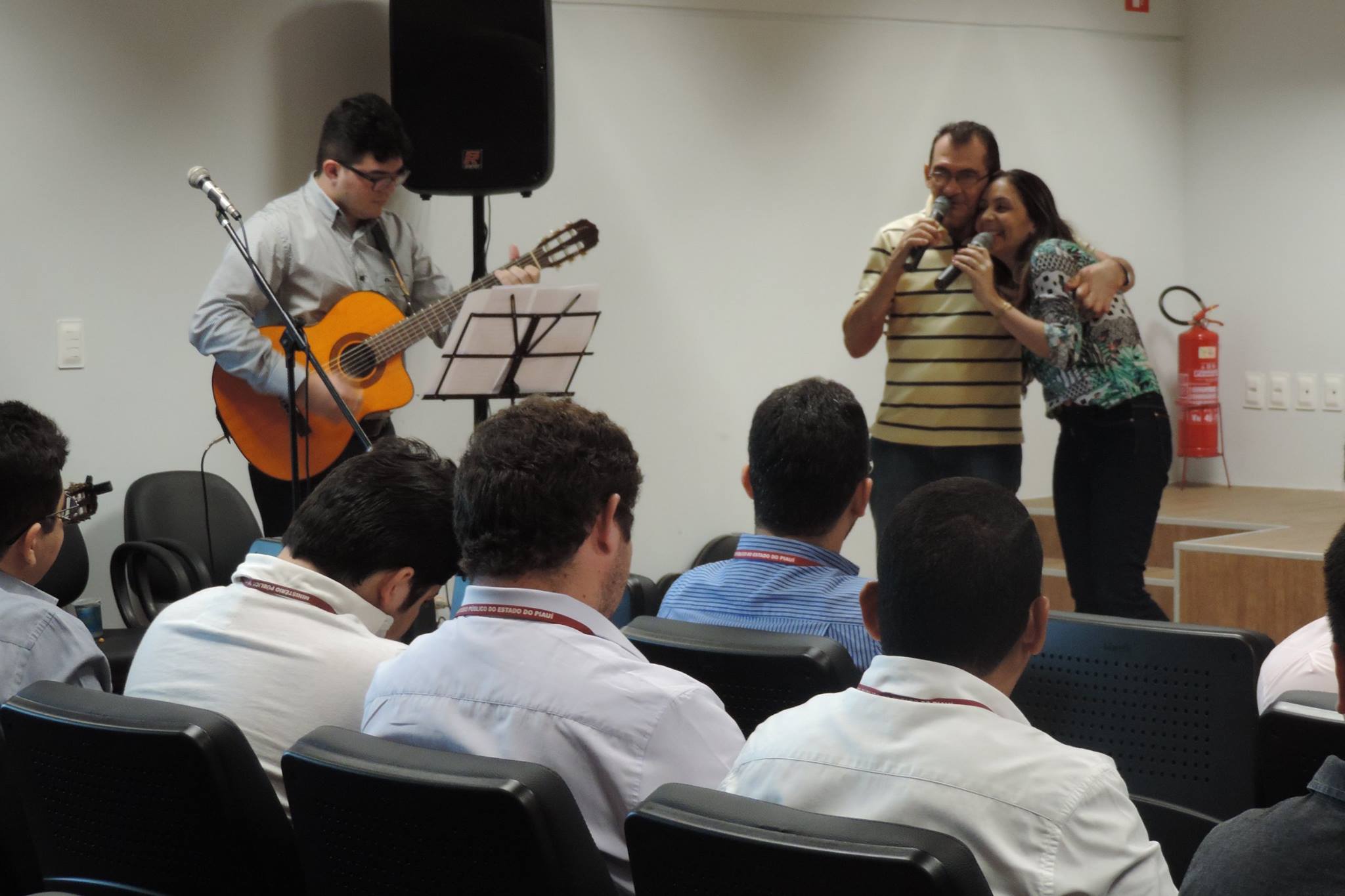 Duas pessoas cantando um abraça o outro