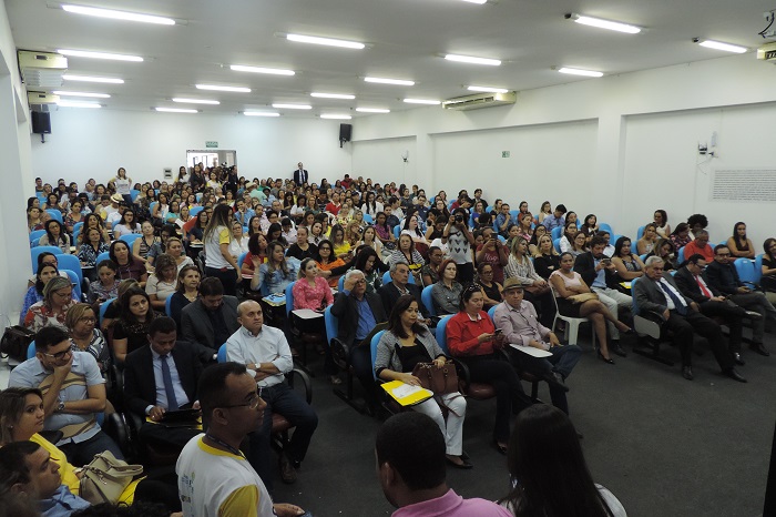 Fotos de pessoas sentadas num auditório, outras de pé caminham