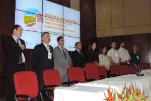 Pessoas de pé, próximo as cadeiras da uma mesa