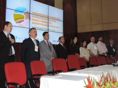 Pessoas de pé, próximo as cadeiras da uma mesa
