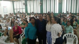 Pessoas sentadas, enquanto quanto pessoas estão pé sorrindo para fotografia