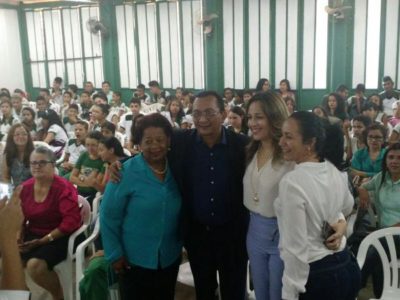 Pessoas sentadas, enquanto quanto pessoas estão pé sorrindo para fotografia
